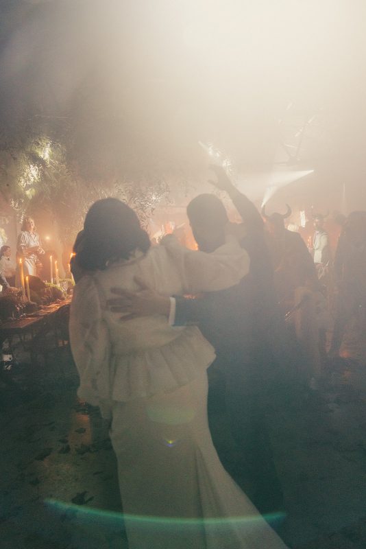 Mesa larga decorada con velas altas, musgo y cristalería en un ambiente estilo bosque encantado para cena de boda elegante.