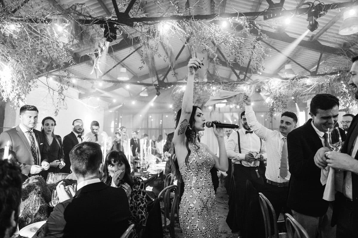 Mesa larga decorada con velas altas, musgo y cristalería en un ambiente estilo bosque encantado para cena de boda elegante.