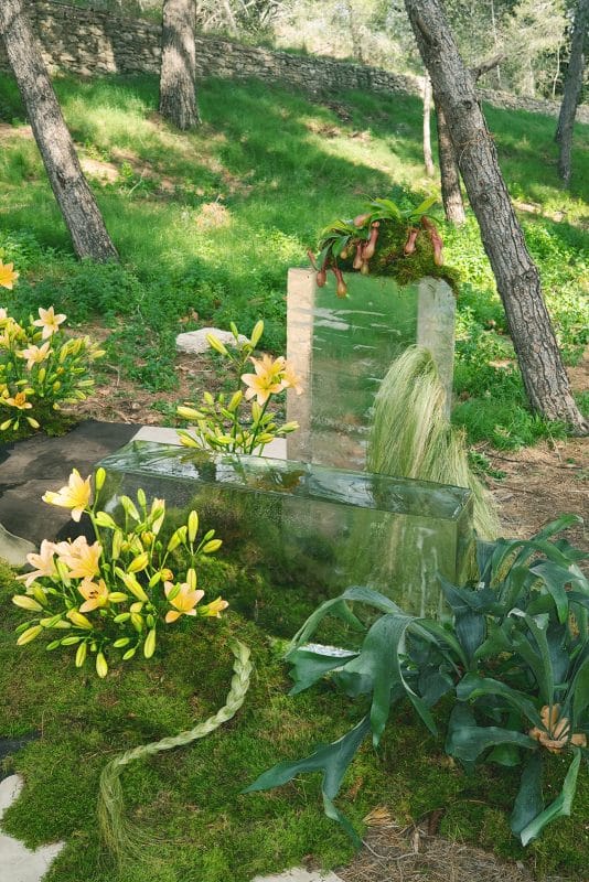 Pareja de novios en ceremonia civil al aire libre con sillas madera, flores frescas y decoración natural entre árboles.