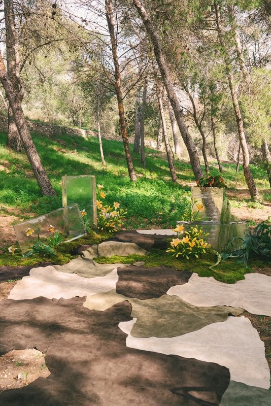 Pareja de novios en ceremonia civil al aire libre con sillas madera, flores frescas y decoración natural entre árboles.