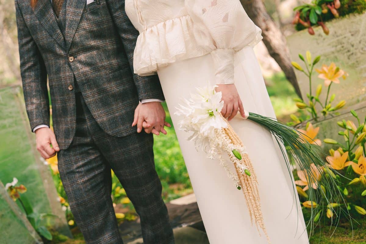 Pareja de novios en ceremonia civil al aire libre con sillas madera, flores frescas y decoración natural entre árboles.